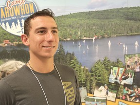 Max Muszynski, from Camp Arowhon in Algonquin Park, stands in front of a lake scene as he mans his booth at a summer job fair at Queen's University in Kingston, Tuesday. 
MICHAEL LEA\THE WHIG STANDARD\QMI AGENCY