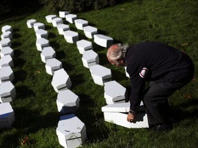 A member of the anti-abortion association "Right to Life", wearing a sticker that reads "Zero abortion", picks up mock coffins of children after a protest in Madrid Oct. 31, 2013. 
REUTERS/QMI Agency