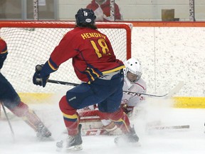 Harrison Hendrix of the Queen's Gaels gives Royal Military College Paladins goaltender Evan Deviller a bit of a snow shower as Deviller smothers a shot in the first period of an Ontario University Athletics hockey game at Constantine Arena on Tuesday night. (Tim Gordanier/The Whig-Standard)