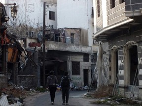 People walk along a damaged street in the besieged area of Homs on January 21, 2014. (REUTERS/Yazan Homsy)