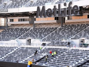 Stadium workers clean snow from stands during the Super Bowl XLVIII preparations in East Rutherford, N.J., on Wednesday, Jan. 22, 2014. (Joe Camporeale/USA TODAY Sports)
