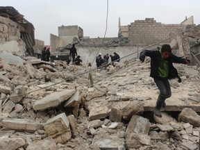 A boy jumps on the rubble of damaged buildings at a site hit by what activists said was an air raid by forces loyal to Syrian President Bashar Al-Assad, in Aleppo's al-Marja district on January 23, 2014. (REUTERS/Mahmoud Hebbo)