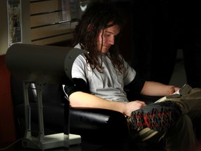 Nikolas McKay reads a book next to a new SAD light at the Stanley Milner Library in Edmonton, AB., on Thursday, Jan 24, 2014. The full spectrum lights helps Seasonal Affective Disorder.  Perry Mah/Edmonton Sun