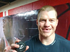 Chris Neil holds the puck with which he scored his 100th goal, becoming the 11th Senator to reach the milestone. BRUCE GARRIOCH/Ottawa Sun