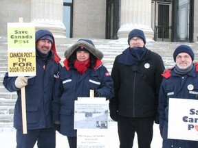 Postal workers, along with Ben Zorn (centre right), president of the Winnipeg Chapter of the Canadian Union of Postal Workers, hold up signs to rally Winnipeggers to support door-to-door service, Jan. 25, 2014. (KRISTIN ANNABLE/Winnipeg Sun)