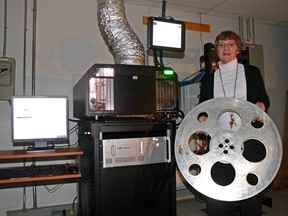 CHRIS ABBOTT/TILLSONBURG NEWS
Broadway Cinemas manager Annete Pye, holding an old film reel, stands next to a digital projector, which was installed in July 2013, in operation Wednesday night. A new surround sound system was also introduced in July.