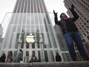 A man poses for a photo in front of the Apple store on 5th Avenue in New York, Dec. 26, 2013.  REUTERS/Carlo Allegri