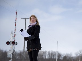 Sharon Jobson holds copies of three lawsuits served to her as she stands at the level crossing on Pratt Siding where her 22-year-old son, John Jobson, collided with a train near Newbury, Ontario in 2011.  Jobson, who in the latest lawsuit is being sued by Via Rail for $2.3 million, is pictured at the crossing on Monday January 27, 2014. CRAIG GLOVER/The London Free Press/QMI Agency