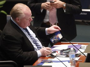Toronto Mayor Rob Ford autographs photos of himself at Toronto city council special meeting to consider the 2014 budget on Wednesday January 29, 2014. (Michael Peake/Toronto Sun)