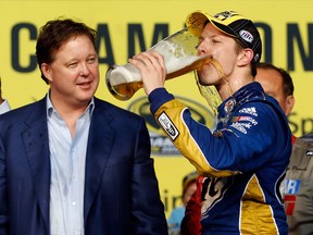 Brad Keselowski, driver of the #2 Miller Lite Dodge, drinks a beer in front of NASCAR chairman and CEO Brian France in Champions Victory Lane after winning the series championship. (Chris Graythen/Getty Images/AFP)
