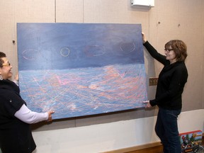 Kingston artists Devalle, left, and Jane Derby hang artwork at the Kingston Frontenac Public Library’s main branch on Princess Street on Thursday for the upcoming Art Slam exhibition by the Organization of Kingston Women Artists. (Ian MacAlpine/The Whig-Standard)
