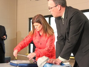 Above: Rona Ambrose, federal health minister, and Mike Hoffman, Heart and Stroke Foundation manager of national AED programs give a demonstration on how easy to use the installed AED units will be in Legal, Alta., on Jan. 22. - Karen Haynes, Reporter/Examiner
