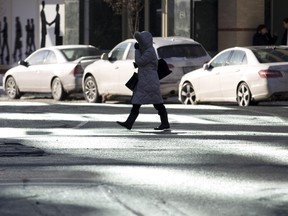 A woman walks through pools of sunlight reflected onto the intersection of Dufferin Avenue and Richmond Street from a nearby office building in London, Ontario on Wednesday January 29, 2014. (CRAIG GLOVER, The London Free Press)