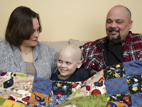 Andrea Stevens, left, sits on the couch with her youngest son Lucas and husband Kevin under the handmade quilt that was given to Lucas to help him his battle with cancer. Lucas was diagnosed with acute lymphocytic leukemia in September 2013. The quilt includes pictures and handwritten well wishes from his teachers and classmates at John XXIII Catholic School. JULIA MCKAY/The Whig-Standard
