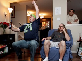 From left, Seattle Seahawks fan Jeff Cummings reacts to a play while watching the Super Bowl with friends Jay Bardyla and K.J., at Cummings' Hazeldean home on Sunday. David Bloom/Edmonton Sun