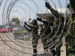 Soldiers set up a barbed-wire fence at a government office where Prime Minster Yingluck Shinawatra had been holding a meeting as anti-government protesters gather outside in Bangkok February 3, 2014.  REUTERS/Athit Perawongmetha