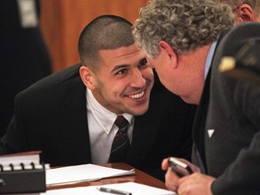 Former New England Patriots tight end Aaron Hernandez (left) smiles at his attorney, Michael Fee, as he appears in court at the Fall River Justice Center in Fall River, Massachusetts December 23,  2013. (REUTERS/Matt Stone/Pool)