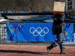 A worker holding a box walks past the Olympic rings at the Rosa Khutor Alpine Centre in the mountain cluster February 2, 2014 prior to the start of 2014 Sochi Winter Olympic Games. (AFP PHOTO/FABRICE COFFRINI)