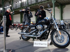 Cameramen shoot the 1,585 cc Harley Davidson Dyna Super Glide, donated to Pope Francis last year and signed by him on its tank, which is displayed as part of Bonham's Les Grandes Marques du Monde vintage and classic cars sale at the Grand Palais in Paris, February 5, 2014. (BENOIT TESSIER/REUTERS)