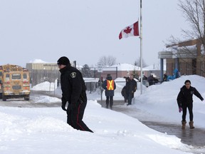 An Orangeville police officer stands outside St. Benedict Elementary School in Orangeville on Thursday, February 6, 2014. The school is flying its flag at half-staff after the death of student Zachary Currie, 9, in the snow near his home. (Craig Robertson/Toronto Sun)