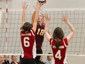Bridget Mulholland of the Regiopolis-Notre Dame Panthers tips the ball past Sydenham Golden Eagles blockers Ashley Grant, left, and Sarah Watson during a Kingston Area Secondary Schools Athletic Association senior girls volleyball match at Regi on Thursday. After dropping the first two sets, the Panthers came back to win the battle of undefeated teams, 3-2, and finish the regular season 12-0. (Tim Gordanier/The Whig-Standard)