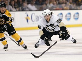 Pittsburgh Penguins defenceman Kris Letang (right) tries to control the puck while going down as Boston Bruins left winger Brad Marchand looks on during NHL play at TD Garden. (Winslow Townson/USA TODAY Sports)