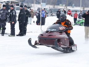 Spectators look on as a snowmobile races down the track during drag races on Moira Lake.