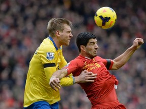 Liverpool's Luis Suarez (right) is challenged by Arsenal's Per Mertesacker during English Premier League play at Anfield Stadium in Liverpool February 8, 2014. (REUTERS/Nigel Roddis)