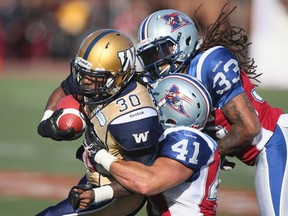 Winnipeg Blue Bombers' Will Ford (30)  is tackled by Montreal Alouettes Dwight Anderson (33) and Shea Emry (41) during the second half of their CFL football game in Montreal, October 8, 2012.  REUTERS/Christinne Muschi (CANADA - Tags: SPORT FOOTBALL)