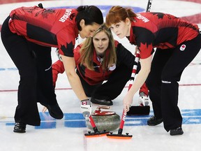Team Canada skip Jennifer Jones delivers a shot as second Jill Officer (left) and first Dawn McEwen sweep during their women's curling round robin game against Great Britain at the 2014 Winter Olympics in Sochi, Russia, Feb. 12, 2014. (AL CHAREST/QMI Agency)