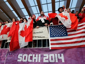 Fans of Canada and the U.S. cheer athletes during the men's luge doubles competition at the 2014 Sochi Winter Olympics in the Sanki Sliding Center, Sochi, February 12, 2014.   
REUTERS/Murad Sezer