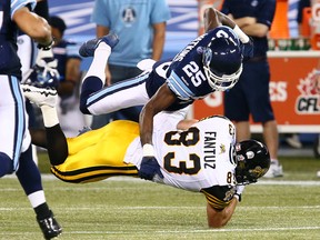 Pat Watkins of the Toronto Argos takes down Andy Fantuz of the Hamilton Tigercats during CFL action at the Rogers Centre in Toronto, Ont. on October 4, 2013. Dave Abel/Toronto Sun