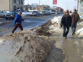 Pedestrians make their way through the barrier-like snowbanks of the midtown section of Princess Street. 
File photo