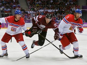 Latvia's Zemgus Girgensons (C) is tripped up by Czech Republic's Marek Zidlicky (L) and Martin Hanzal during the third period of their men's preliminary round ice hockey game at the Sochi 2014 Winter Olympic Games February 14, 2014. (REUTERS)