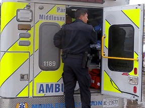 A London police officer investigating a stabbing at 253 Dundas St. stands on the back of an ambulance where the man was being treated before being taken to Victoria Hospital in London on Friday. Mike Hensen/The London Free Press/QMI Agency