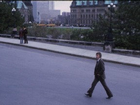 Photo of a 42-year-old Peter Desbarats, glancing into Larry Cornies' camera, feet astride in a purposeful walk across Parliament Hill.