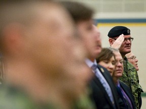 Lt. Col. Scott Long (right), chief of operations of Third Canadian Division Support, salutes during the signing of "Oh Canada" at Guthrie School at C.F.B Edmonton in Edmonton, Alta., on Friday, Feb. 14, 2014. Canadian soldiers will be honoured with a flag lowering ceremony at all Alberta schools on March 12 to recognize the end of Canada's 12-year contribution to the NATO mission in Afghanistan. Ian Kucerak/Edmonton Sun