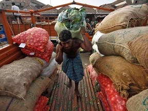 A labourer carries a sack filled with cabbage to load it onto a supply van at a vegetable wholesale market in the southern Indian city of Chennai. While India looks to place itself amongst the world powers, the vast majority of its population continues to live in poverty. 
REUTERS/QMI Agency