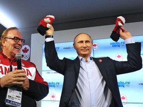 Russia's President Vladimir Putin holds up mittens while standing next to president of the Canadian Olympic Committee Marcel Aubut as he visits Team Canada House at the Olympic Park during the Sochi 2014 Winter Olympics Games, Friday. 
REUTERS/QMI Agency