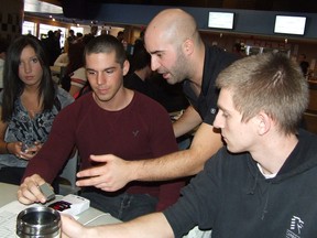 Harold Carmichael/The Sudbury Star     
Marty Dubuc, of Cambrian college's Phyiscal Fitness and Leisure Management Program, centre, checks heart rate monitor data of student Kevin Jeanveau, 21, right, with student Dan Renaud, also 21, Friday in the college's Student Centre.