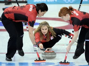 Canada's Jennifer Jones trows the stone as her team mates Jill Officer (L) and Dawn McEwen sweep during the Women's Curling Round Robin Session 9 against Russia at the Ice Cube Curling Center during the Sochi Winter Olympics on February 15, 2014. (AFP PHOTO/ANDREJ ISAKOVIC)