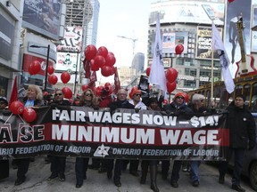 A group gathers at Dundas Square holding signs and chanting to have the minimum wage raised to $14 an hour  on Saturday February 15, 2014. in Toroonto. (Veronica Henri/Toronto Sun)