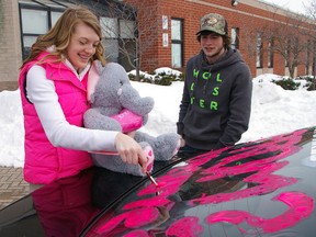 Tori Sponer, left, gives Dustin Owen her answer to his promposal Friday in St. Thomas by painting in the Yes box on the back window of his car.