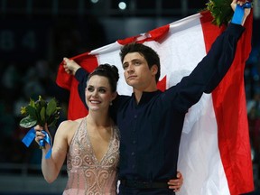 Canada's Tessa Virtue and Scott Moir wave their flag after the flower ceremony for the figure skating ice dance free dance program at the Sochi 2014 Winter Olympics, February 17, 2014. (REUTERS)