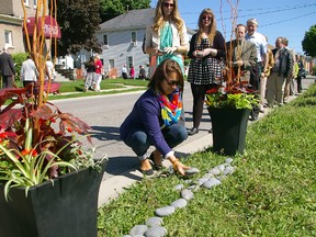 Shelley Boyes places a stone symbolizing the foundation on which a new Women's Place emergency shelter is to be built, Monday, June 3, 2013 in St. Thomas at a $1 million community capital campaign kickoff.