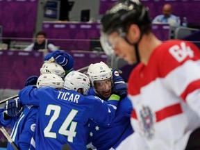 Slovenia's Anze Kopitar (2nd R) celebrates his goal with teammates as Austria's Andre Lakos (foreground) skates past during the first period of their men's ice hockey playoffs qualification game at the 2014 Sochi Winter Olympics February 18, 2014.  (REUTERS)
