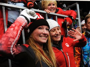 Canada's Kaillie Humphries (right) and Heather Moyse are surrounded by family after their gold medal win in bobsled at the Sanki Sliding Center in Sochi, Russia, Feb. 19, 2014. (DIDIER DEBUSSCHERE/QMI Agency)