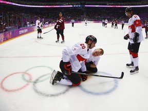 Canada's John Tavares (20) is attended to by a trainer after being injured playing against Latvia, as teammate Patrick Sharp (R) looks on, during the second period of their men's quarter-finals ice hockey game at the Sochi 2014 Winter Olympic Games February 19, 2014. (REUTERS)