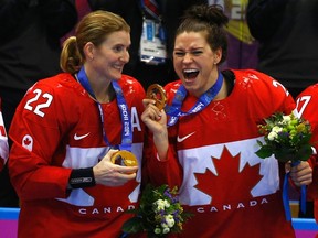 Canada's Hayley Wickenheiser (L) and Natalie Spooner celebrate with their gold medals after their team defeated Team USA in overtime in the women's ice hockey final game at the 2014 Sochi Winter Olympics, February 20, 2014.  (REUTERS)