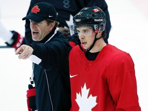 Canadaian men's hockey head coach Mike Babcock gives directions during practice as Sidney Crosby skates by at the 2014 Sochi Winter Olympics, Feb. 18, 2014. (JIM YOUNG/Reuters)